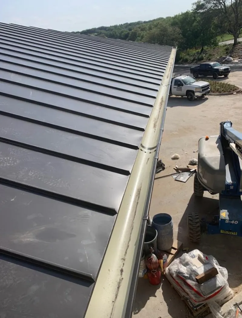 Standing seam panel and gutter detail on a metal roofing jobsite in Newton
